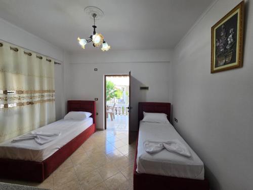 a bedroom with two beds and a chandelier at Hotel Bar Pizzeria Verona in Ksamil