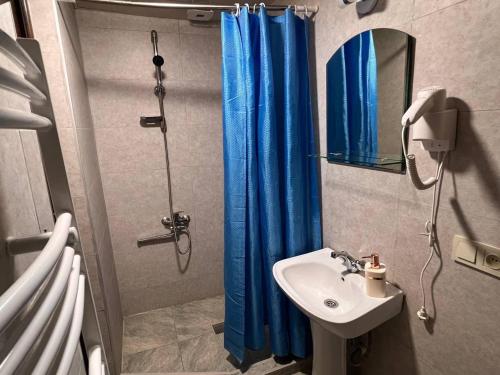 a bathroom with a blue shower curtain and a sink at Memory- borjomi in Borjomi