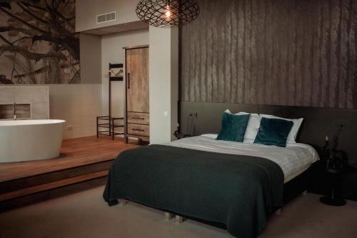 a bedroom with a large bed and a bath tub at Boutique Hotel De Oude Veste in Hellevoetsluis