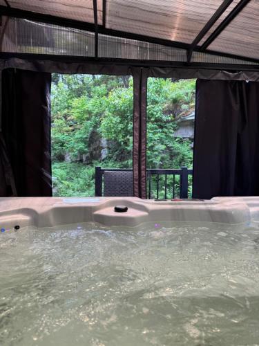 a jacuzzi tub in a room with a window at The Rowanwood - Muskoka Cottage Retreat in Huntsville