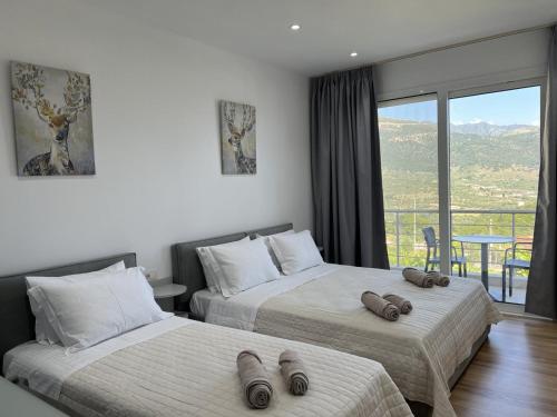 two beds in a hotel room with a balcony at Irene's rooms in Himare