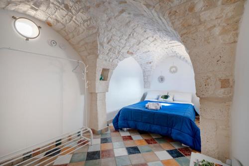 a bedroom with a blue bed in a stone wall at Domus Magistri in Ostuni