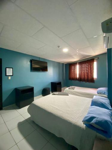 a bedroom with two beds and a blue wall at Hotel Confort in Guayaquil