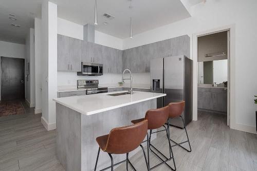 a kitchen with a counter with three chairs and a sink at South Downtown Condo no.308 in Dallas