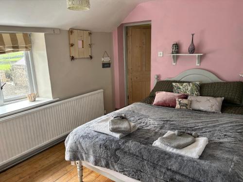 a bedroom with a large bed with pink walls at Cottage Sleeps 4 with Wifi in Llanfairpwllgwyngyll