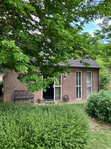 a small brick house with a window and a tree at Forest Vacation Home -fenced garden- in Ewijk