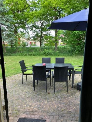 a table and chairs with a blue umbrella at Forest Vacation Home -fenced garden- in Ewijk