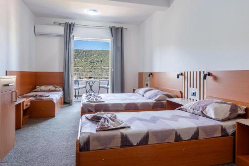 a hotel room with three beds and a window at Villa Petra in Neum