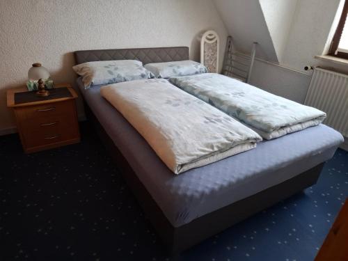 a bed with two pillows and a night stand at Ferienwohnung in Gartenlandschaft in Kassel