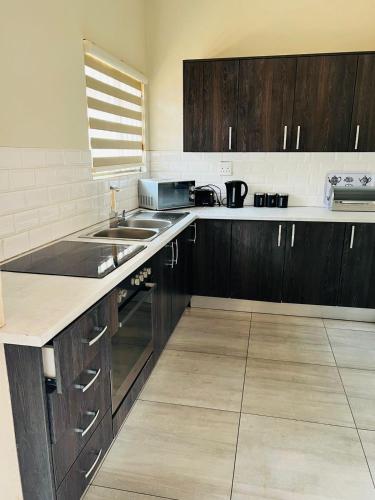 a kitchen with wooden cabinets and a sink and a counter at Ultimate Sky-2 bedroom villa in Pretoria