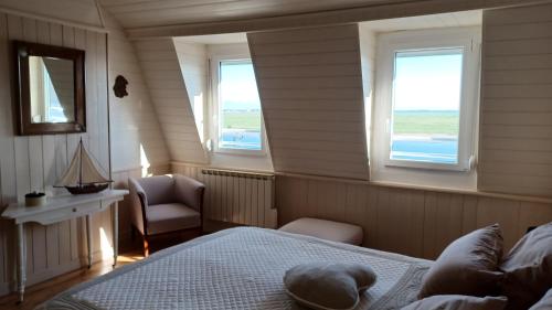 a bedroom with a bed and a chair and windows at L'ESTRAN in Saint-Valéry-sur-Somme