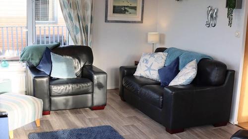 a living room with a leather couch and a chair at 4 Meadow View in Woolacombe
