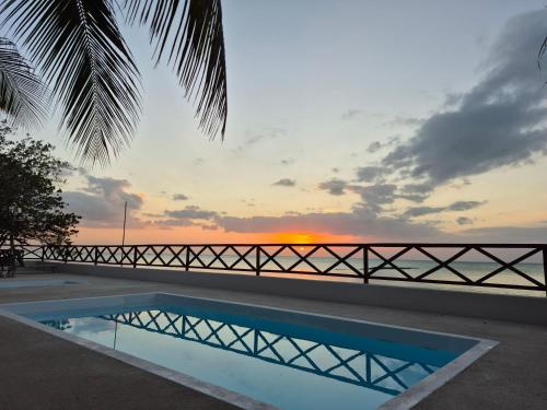 a swimming pool with a sunset in the background at Choby's House Holbox in Holbox Island