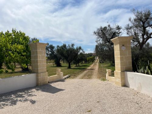 a gate on a dirt road with trees in the background at Villa Mina in Serranova