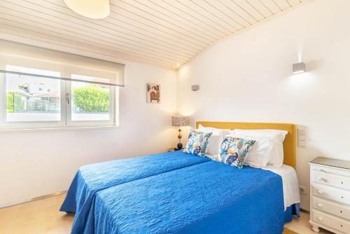 a bedroom with a blue bed and a window at Host In Olivença in Vila Nova de Famalicão