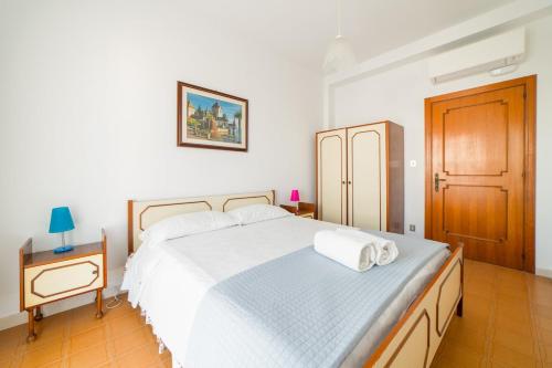 a bedroom with a white bed and a wooden door at Bambinopoli Al Mare in Alba Adriatica