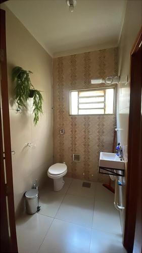 a bathroom with a toilet and a sink and a window at Morada 1000 - Pousada in Frutal