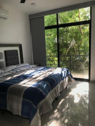 a bedroom with a bed and a large window at Casa Maya in Puerto Morelos