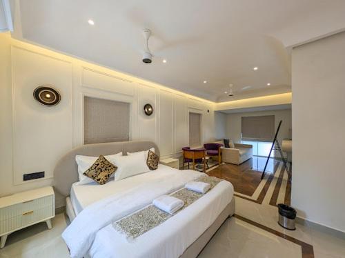 a bedroom with a large white bed and a living room at Finca - the tidal nest in Candolim
