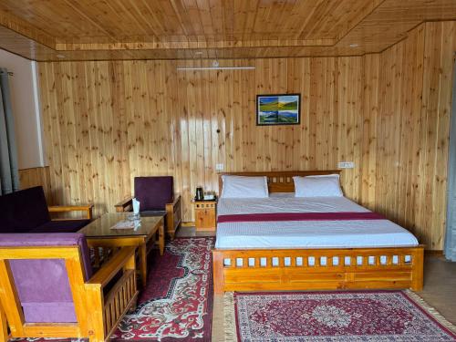 a bedroom with a bed and a table and a chair at Harshil View Home Stay in Harsil