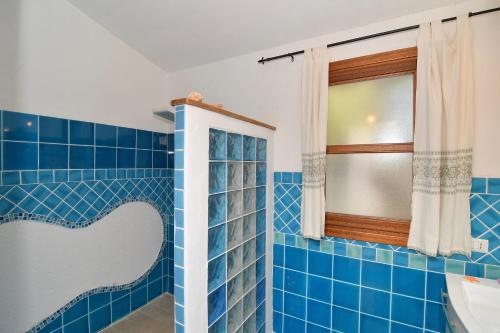 a blue tiled bathroom with a window and a sink at Stazzo La Chèa in Nuragheddu