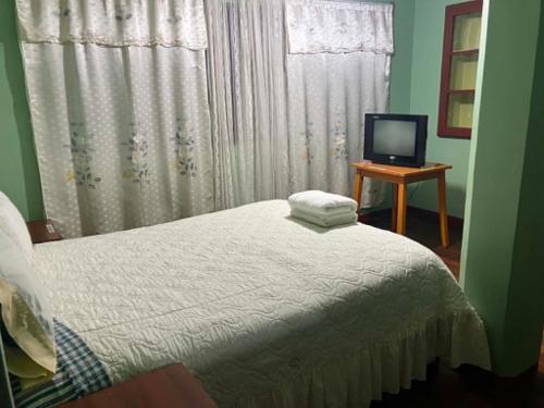 a bedroom with a bed and a television on a table at Imperio Carlos V in Oruro
