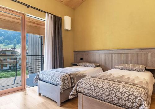 two beds in a room with a balcony at Ciasa Fatati' in Pinzolo