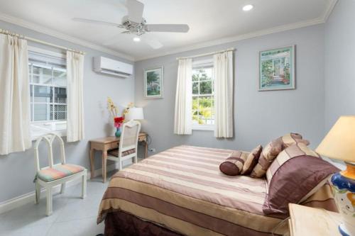 a bedroom with a bed and a desk and windows at The Little White Cottage in Saint Peter