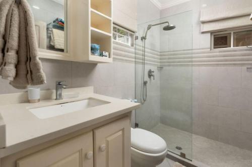 a bathroom with a toilet and a sink and a shower at The Little White Cottage in Saint Peter
