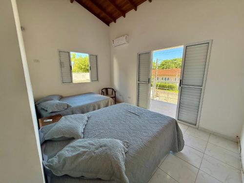 a bedroom with two beds and a balcony at Casa virgínia enseada in Guarujá