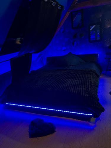 a dark room with a bed with a blue light at Maison love rooms in Tours