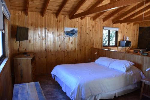 a bedroom with a bed in a wooden room at Los Quenes River Lodge in Los Queñes