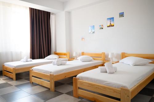 a room with three beds with white sheets at Occidental Wise Transit in Bucharest