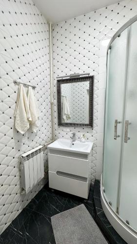 a white bathroom with a sink and a shower at Central Square Apartment in Ternopil