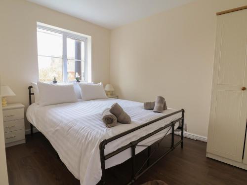 a bedroom with a bed with white sheets and a window at 31 Llys Ogwen in Prestatyn