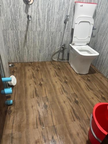 a bathroom with a toilet and a wooden floor at Hotel Shree Ji in Tālbahat