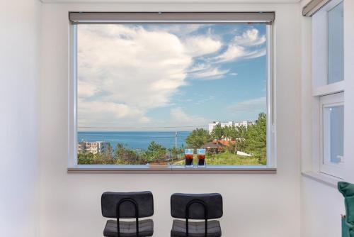 a window with two chairs looking out at the ocean at Donghae aeodalari pension in Donghae
