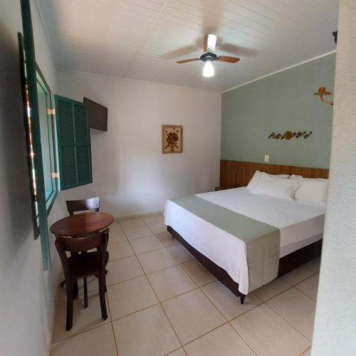 a bedroom with a bed and a chair and a table at Pousada Vila Cocais in Cocais