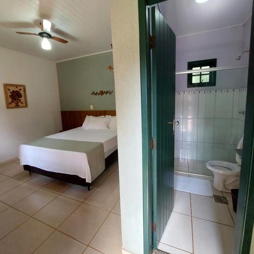 a bedroom with a bed and a bathroom with a toilet at Pousada Vila Cocais in Cocais