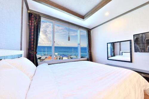 a bedroom with a large bed and a large window at Sokcho otwohouse pension in Sokcho