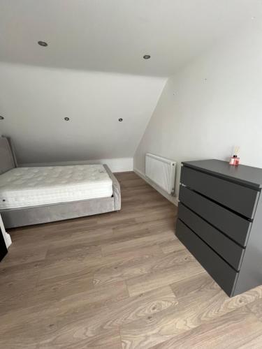 a bedroom with a bed and a dresser at Deluxe family room in Chessington