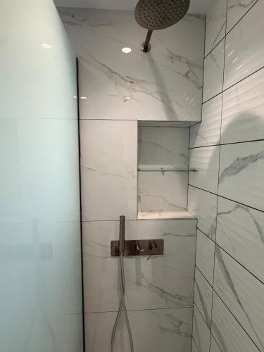 a bathroom with a shower with white marble walls at Sea View Luxury Apartment Beachfront 3BR in Agia Triada