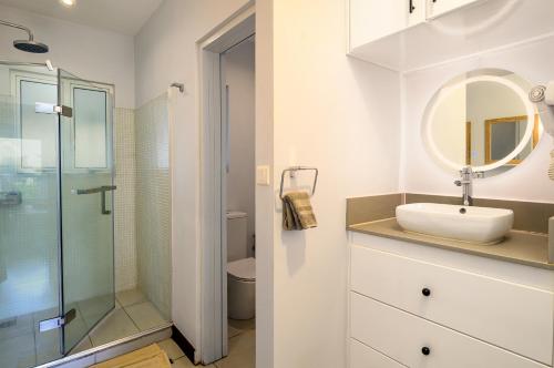a white bathroom with a sink and a shower at Plage Bleue D2 in Trou aux Biches