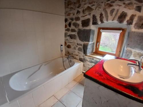 a bathroom with a bath tub and a sink at Le Coudi in Saint-Pierre-le-Chastel