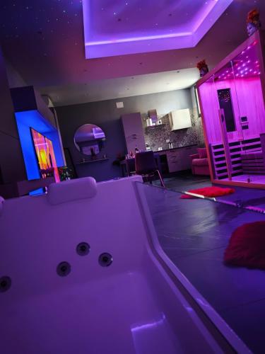 a room with a white tub in a room with purple lights at Suite Romantica con Jacuzzi e Sauna in Porto Empedocle