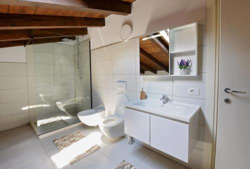 a white bathroom with a toilet and a sink at Villa Madera in Shirokë