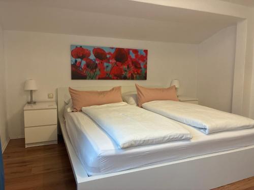 a bedroom with two white beds with a painting on the wall at Ferienwohnung Diwoky in Sankt Gilgen