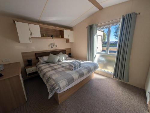 a bedroom with a bed and a large window at Three lochs holiday park Loch view 123 in Balminnoch