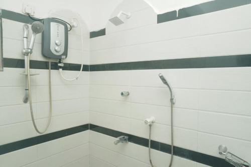 a bathroom with a shower with a phone on the wall at T-Nova Guest House in Trincomalee