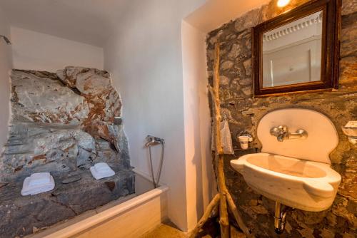 a stone bathroom with a sink and a toilet at Wind Tales in Ermoupoli